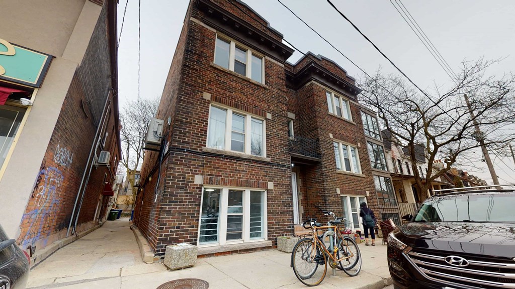 A brown brick building with a bicycle leaning against it.