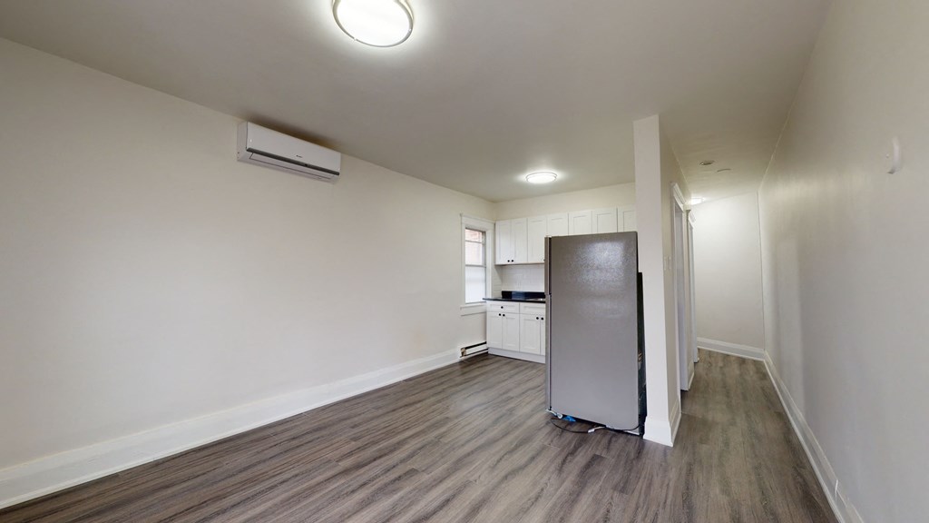 A kitchen area with a refrigerator and a television.