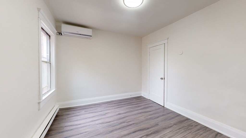 A room with a window and a door is empty and waiting to be furnished.