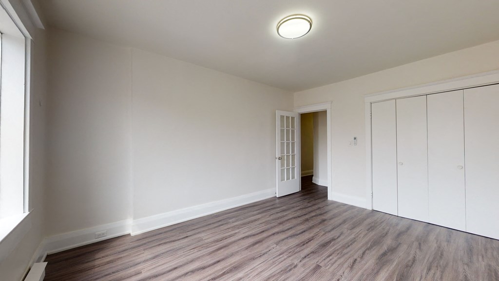 A room with wooden flooring and white walls.