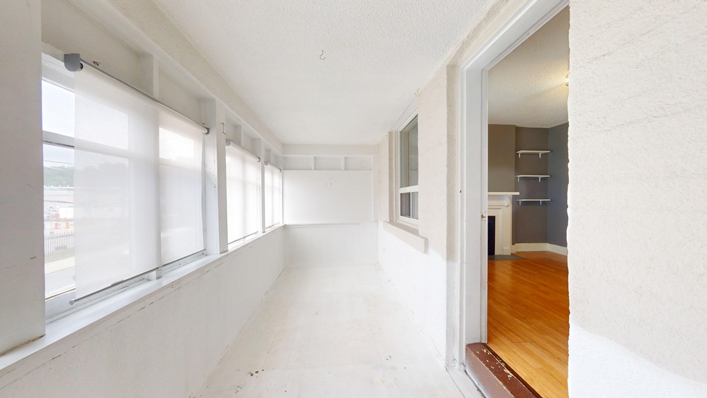 A long, empty hallway with white walls and a wooden floor.