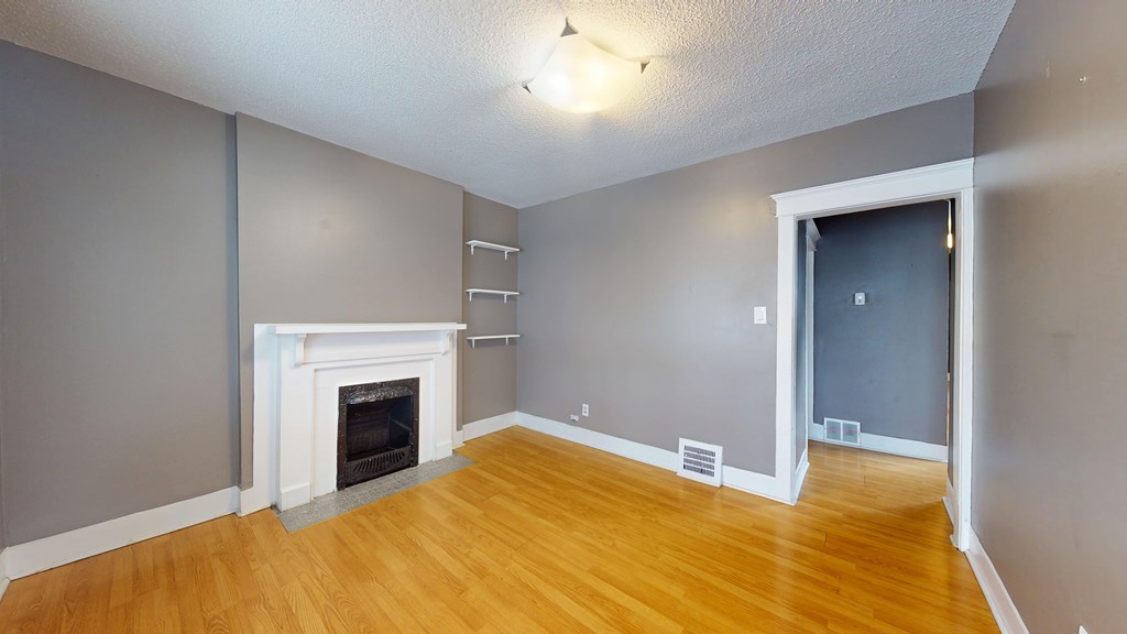 A room with a fireplace and wooden floors.