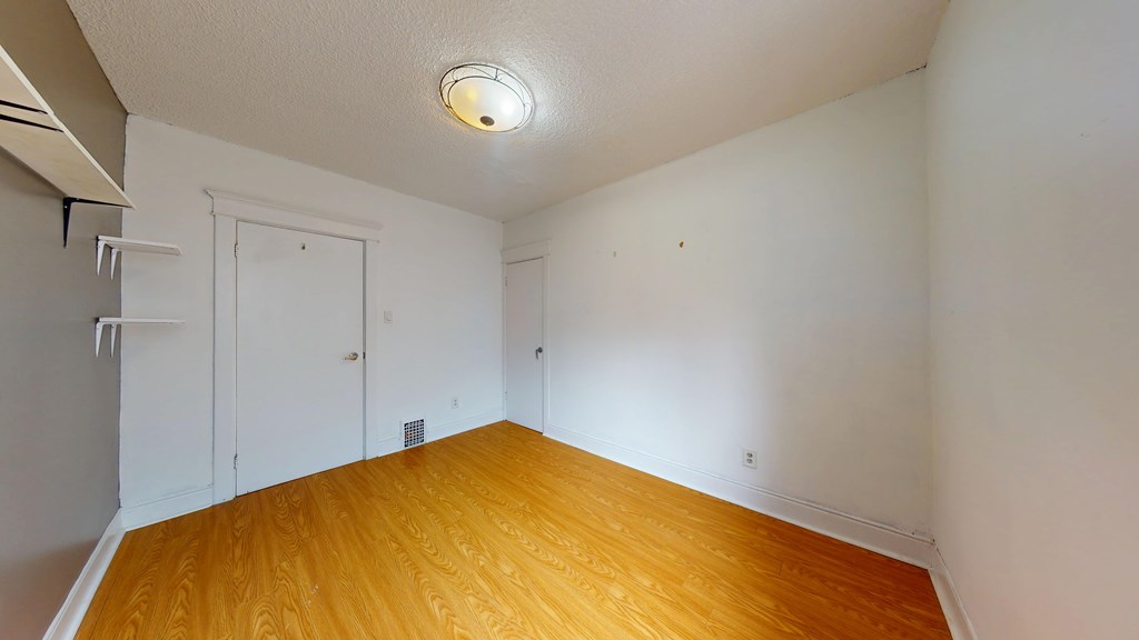 A room with wooden flooring and white walls.