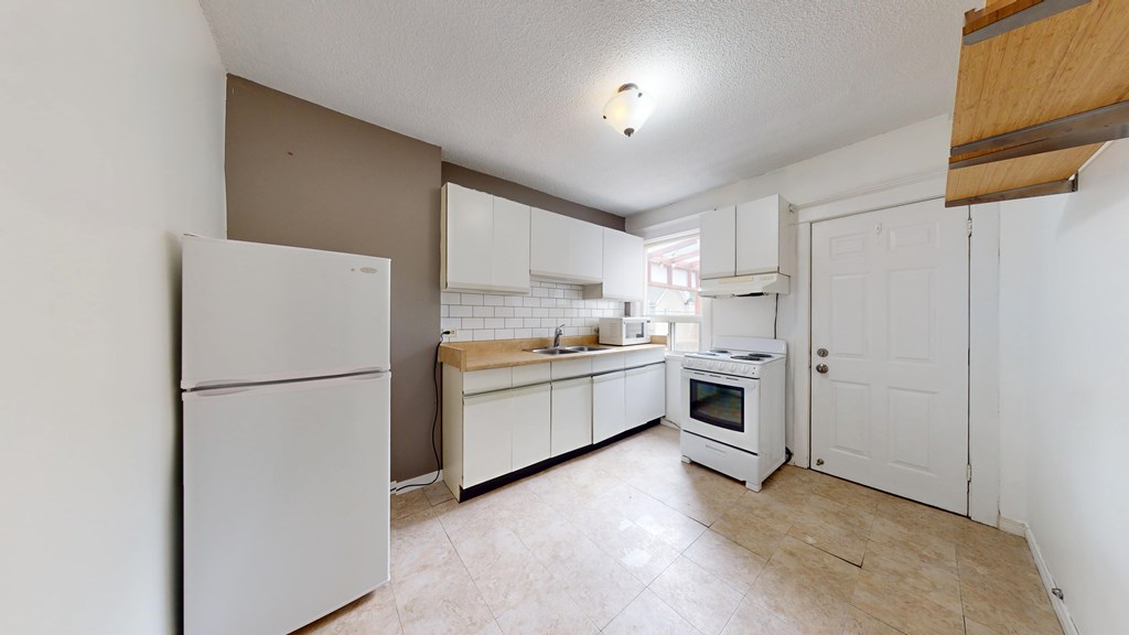 A kitchen with white appliances and a wooden ceiling beam.