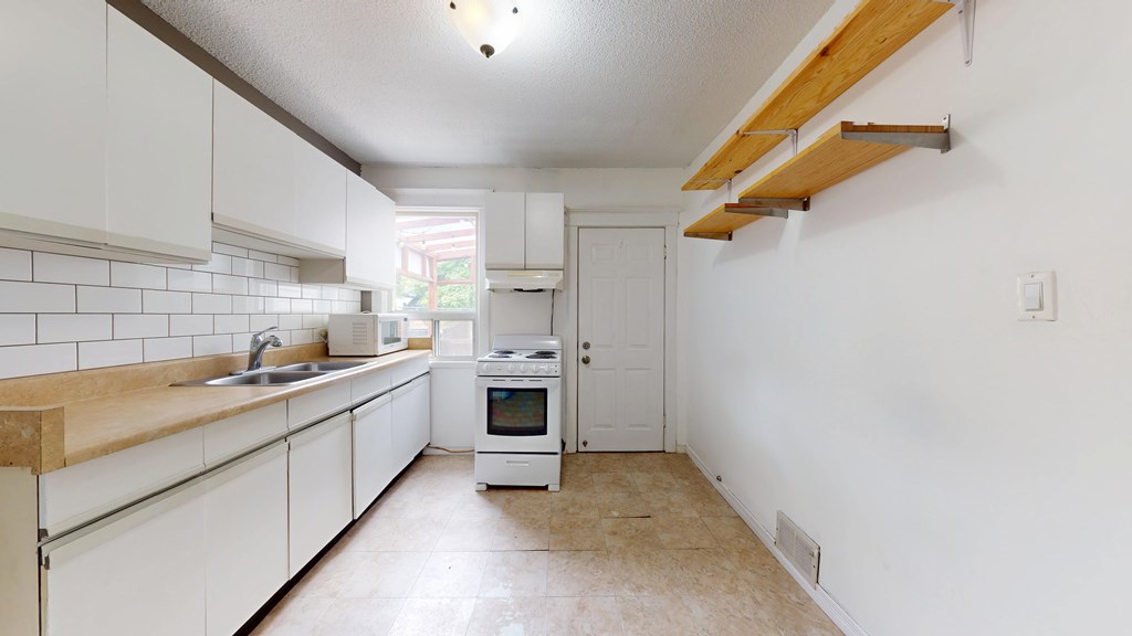 A kitchen with white cabinets and a wooden countertop.