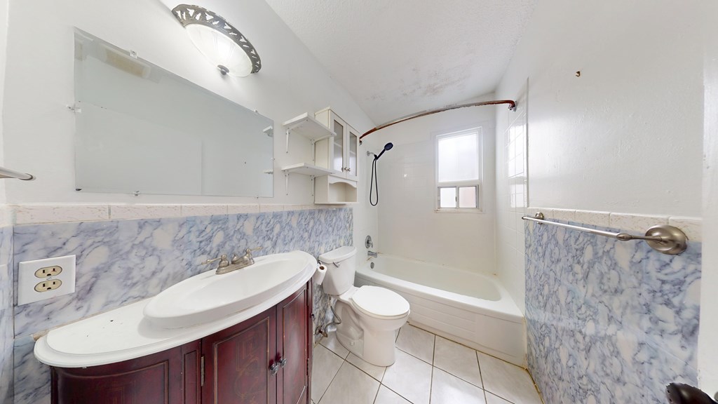 A bathroom with a marble counter top and a white bathtub.