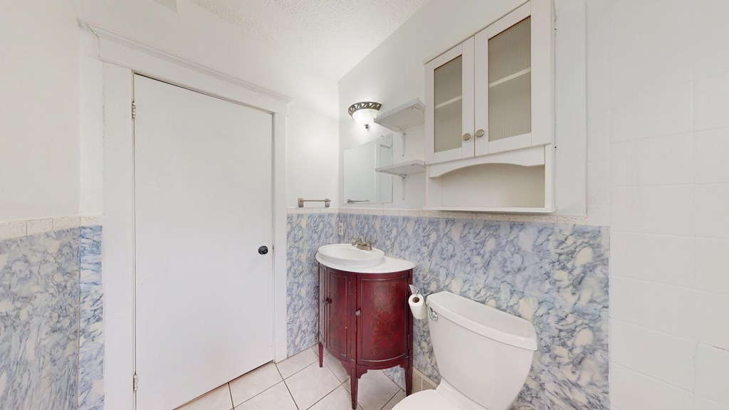 A white bathroom with a red tub and a white toilet.