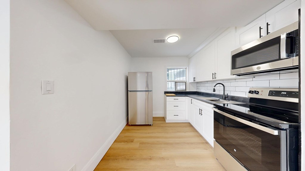 A kitchen with white cabinets and black appliances.