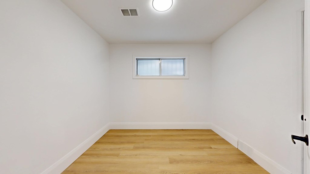A room with a wooden floor and a small window.
