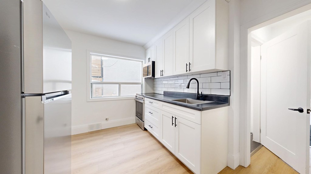 A kitchen with white cabinets and a black countertop.