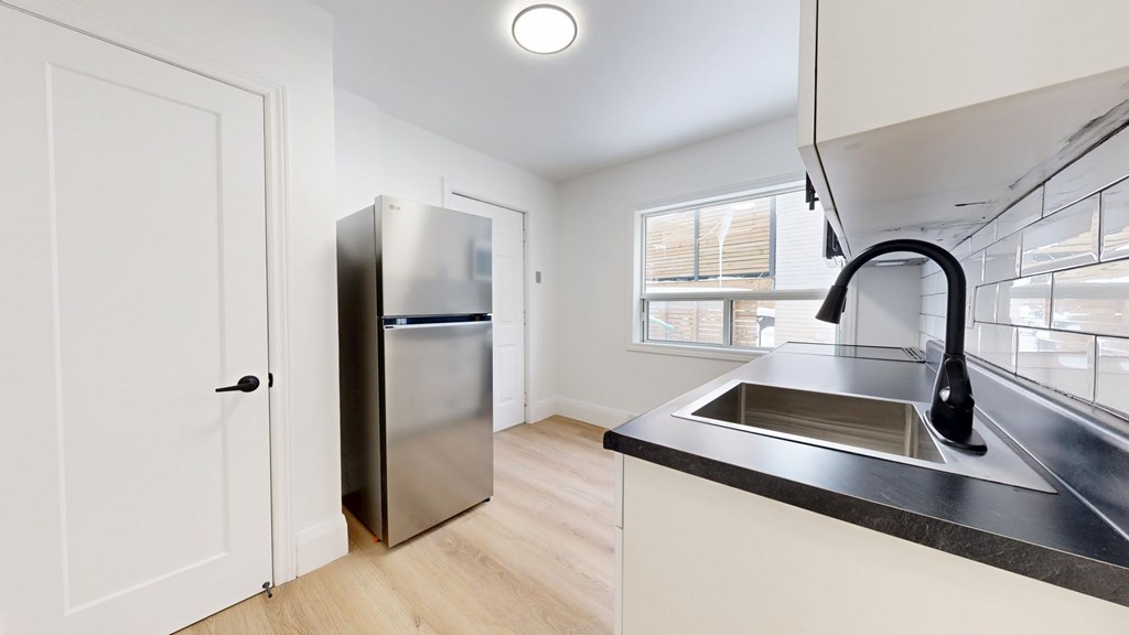 A kitchen with a sink, refrigerator, and a window.