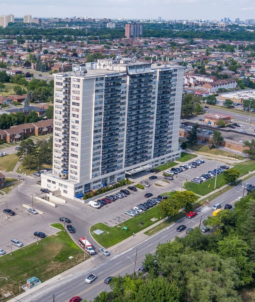 A tall residential building with a parking lot in front.
