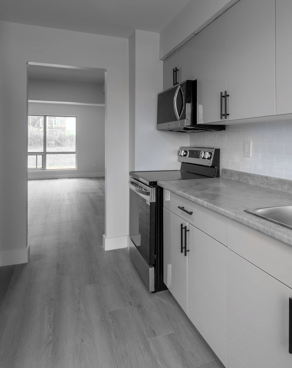 A black and white image of a kitchen with a microwave above the stove.