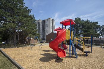A playground with a red slide and a yellow slide.