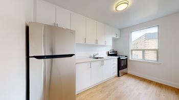 A kitchen with white cabinets and a black fridge.
