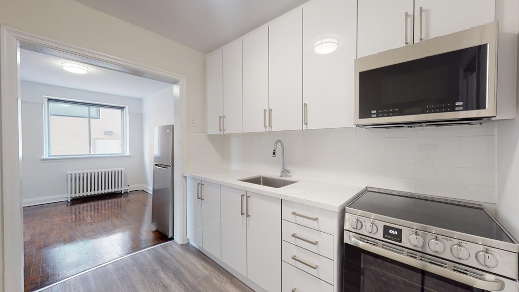 A kitchen with white cabinets and a black microwave.