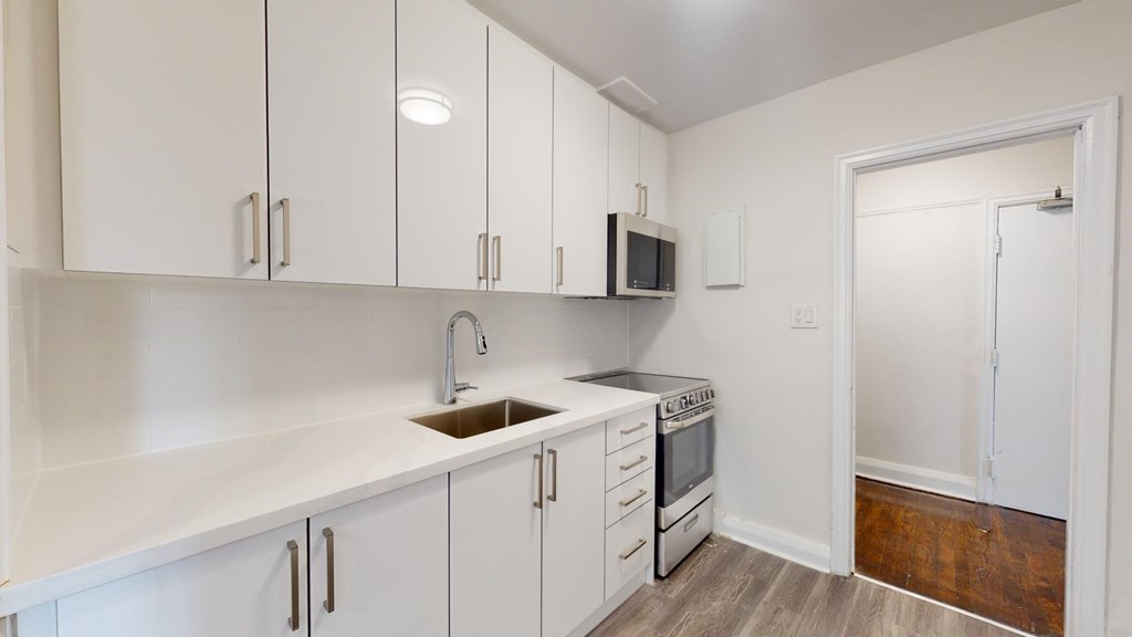 A kitchen with white cabinets and a black microwave.