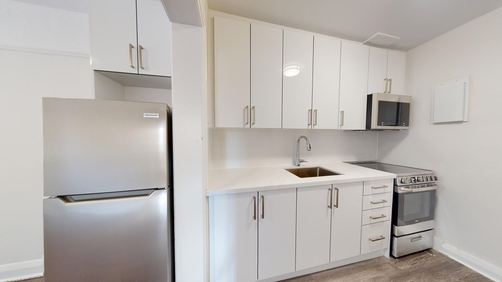 A kitchen with white cabinets and a stainless steel refrigerator.