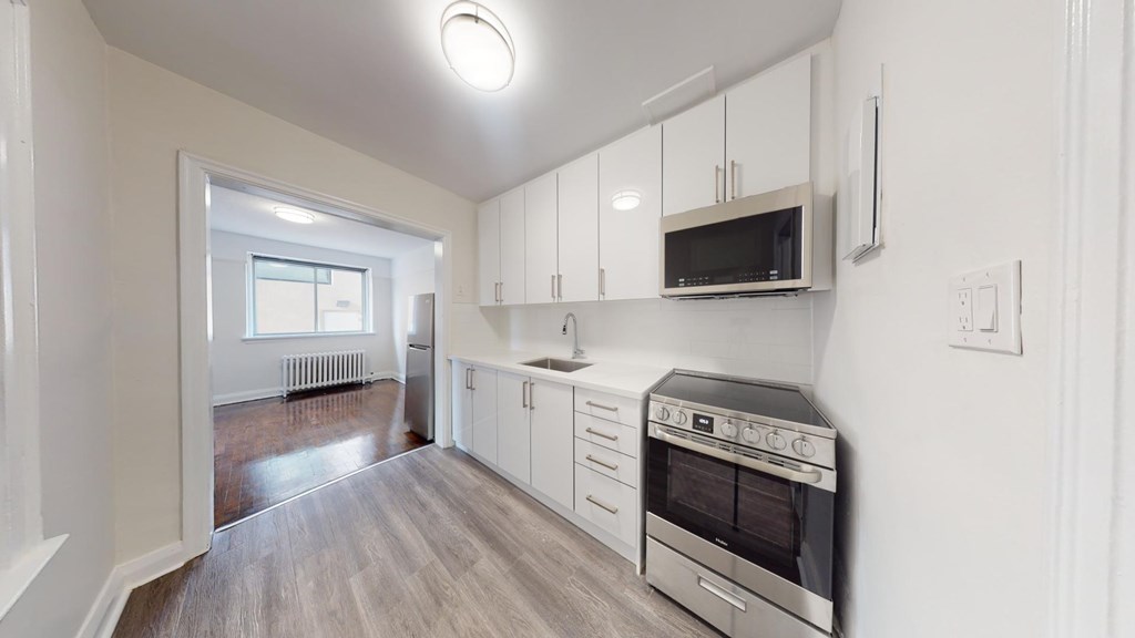 A kitchen with white cabinets and a microwave above the stove.