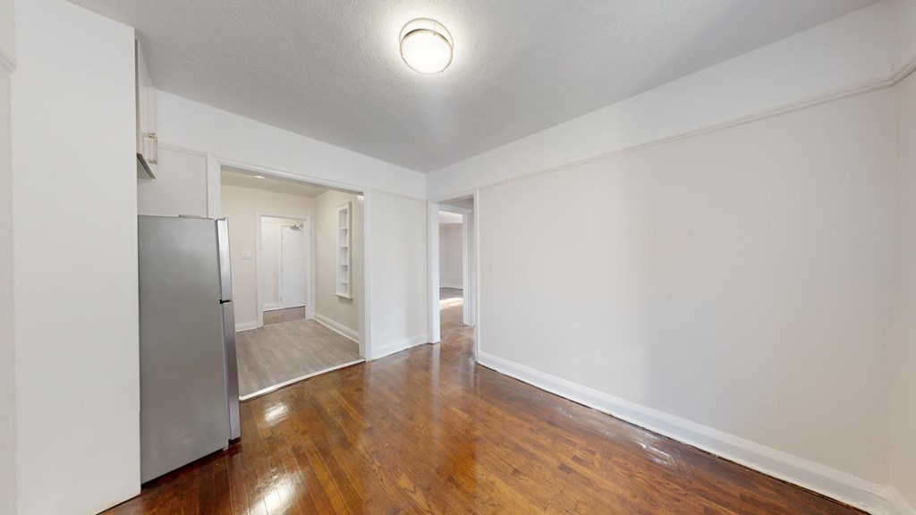 A kitchen with a refrigerator and wooden floors.