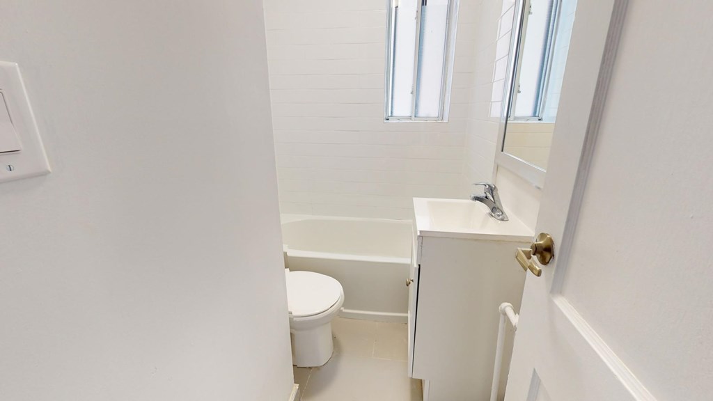 A white bathroom with a toilet, sink, and mirror.
