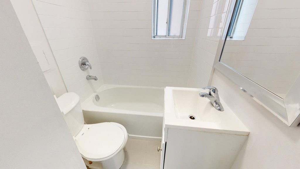 A white toilet sits next to a white sink in a small bathroom.