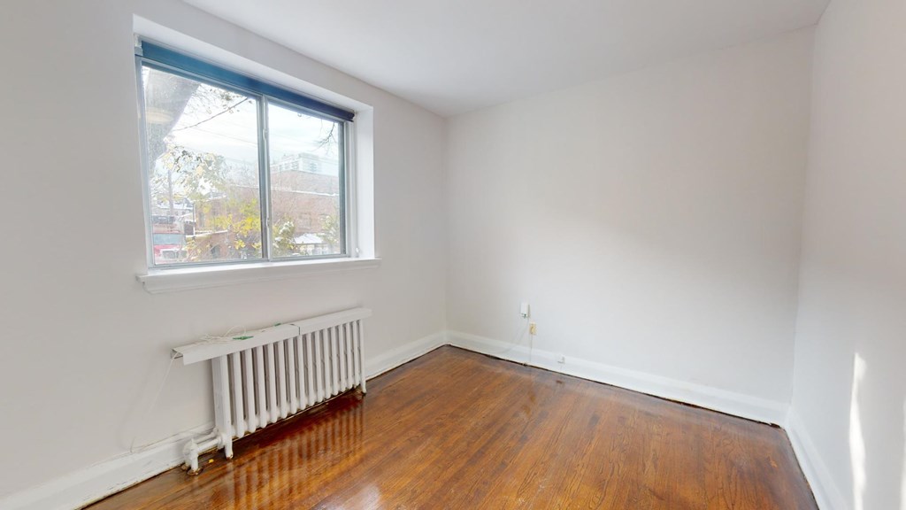 A room with a window and a radiator on the floor.