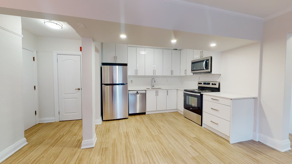 A kitchen with white cabinets and a wooden floor.