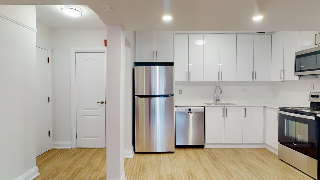 A kitchen with a refrigerator, microwave, and oven.