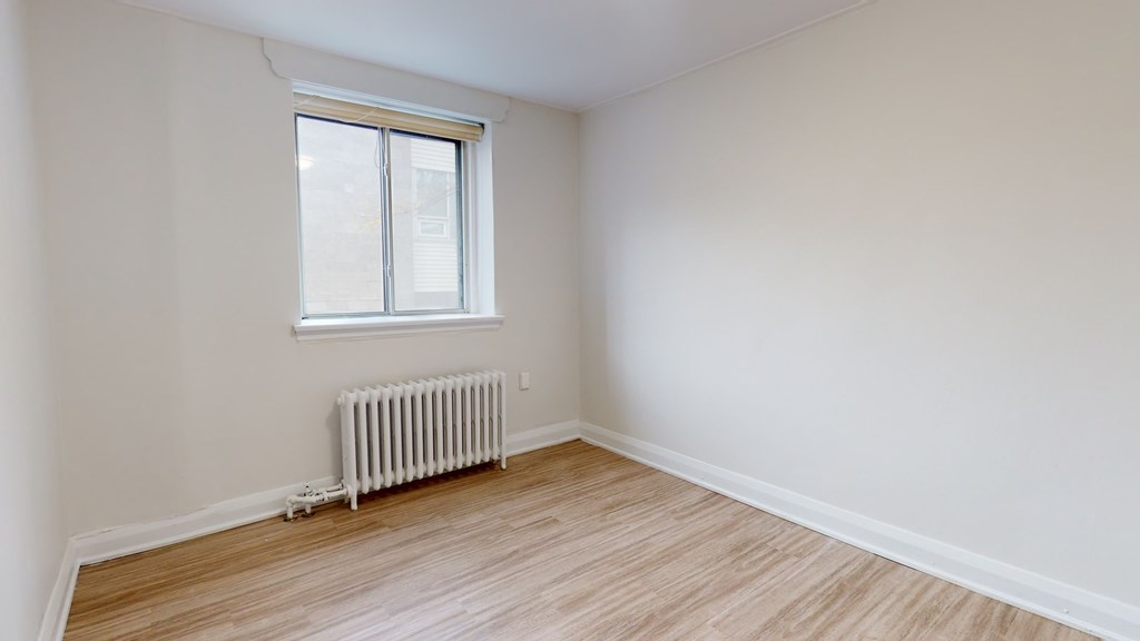 A room with a window and a radiator on the floor.