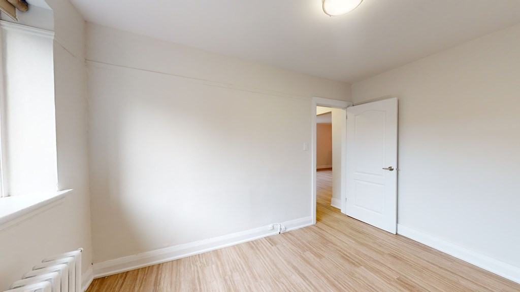 A room with a white door and a window with white blinds.