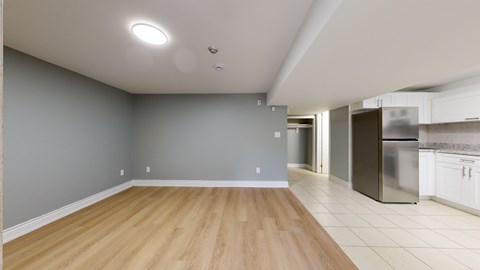 A kitchen with a refrigerator, stove, and oven is visible from the living room.