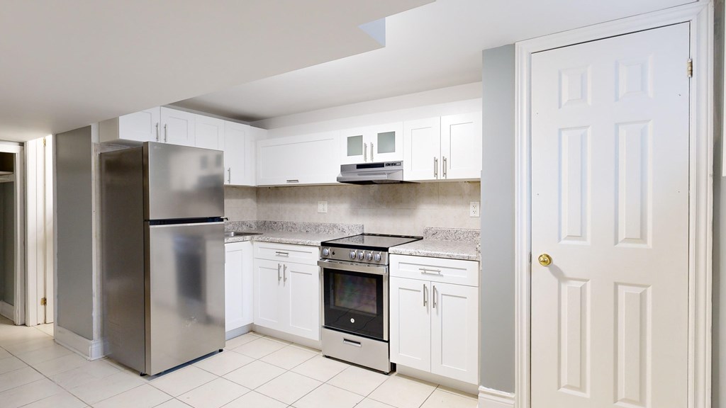 A kitchen with white cabinets and a stainless steel refrigerator.