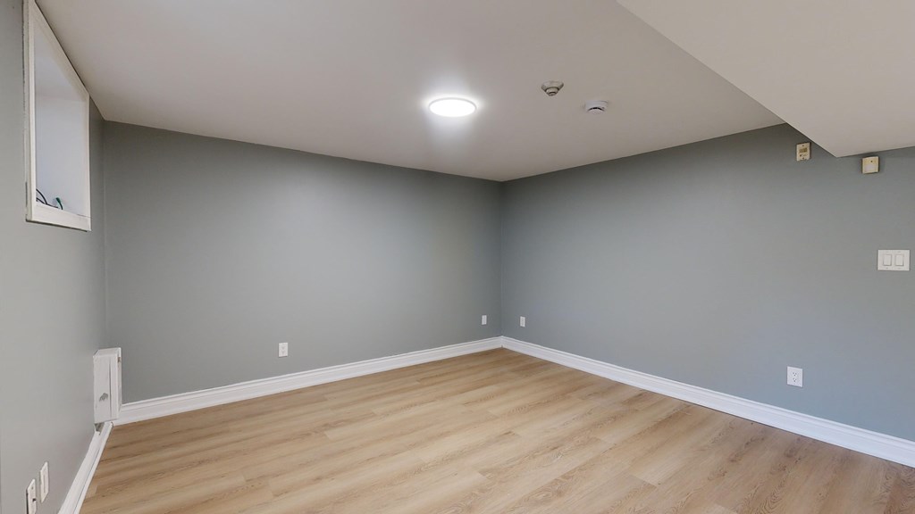 A room with wooden flooring and grey walls.