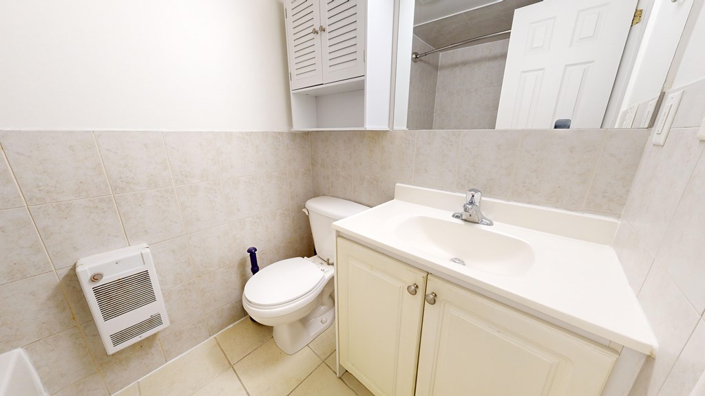 A bathroom with a toilet, sink, and cabinet.