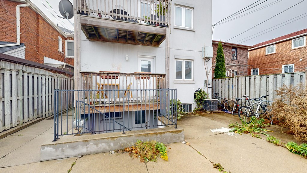 A patio with a table and chairs is surrounded by a fence and a bicycle is parked in the yard.