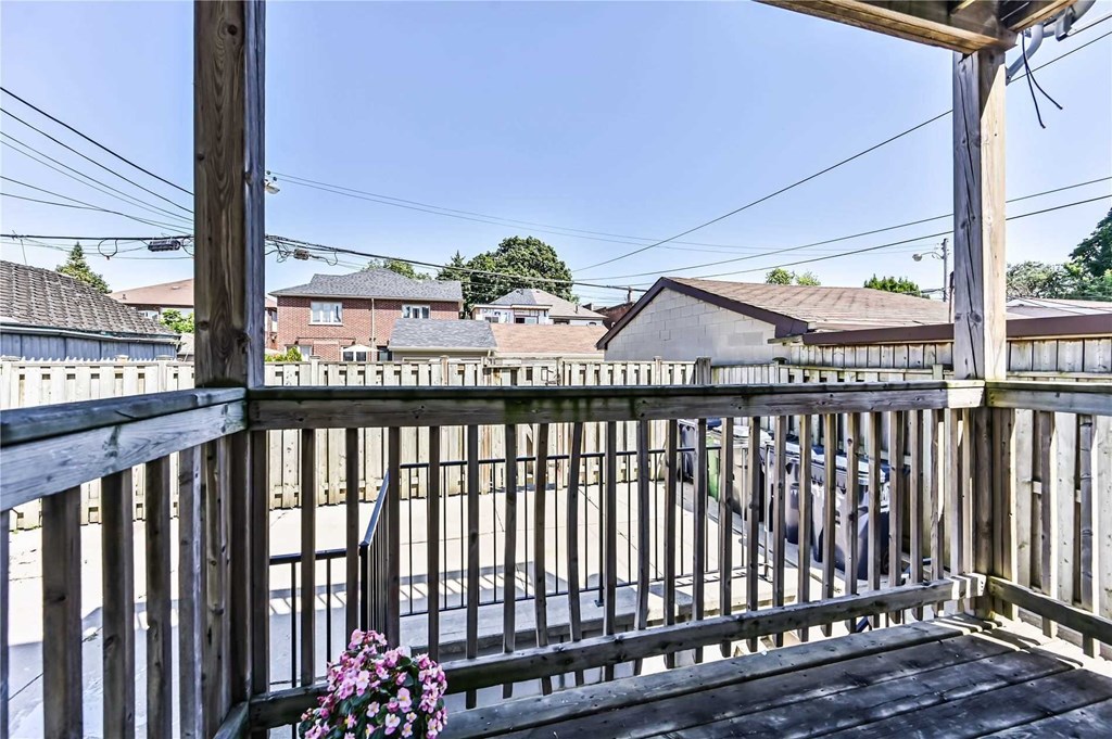 A wooden deck with a metal railing and a potted plant on it.