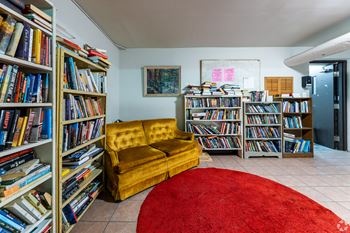 A room with a yellow sofa and bookshelves filled with books.