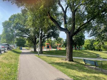 A park with a walking path, trees, and a playground.