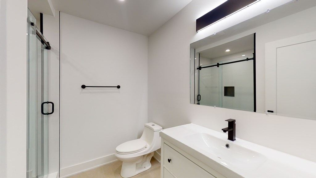 A white bathroom with a toilet, sink, and mirror.