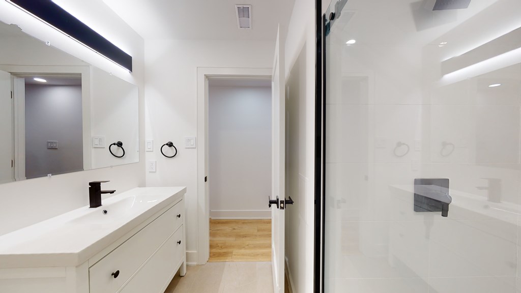 A white bathroom with a sink, mirror, and towel rack.