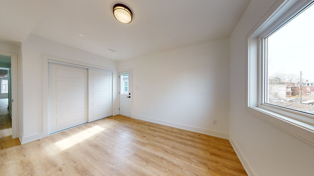 A room with a window and a wooden floor.