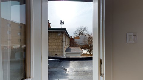A view from inside a room looking out through a glass door to a residential street.