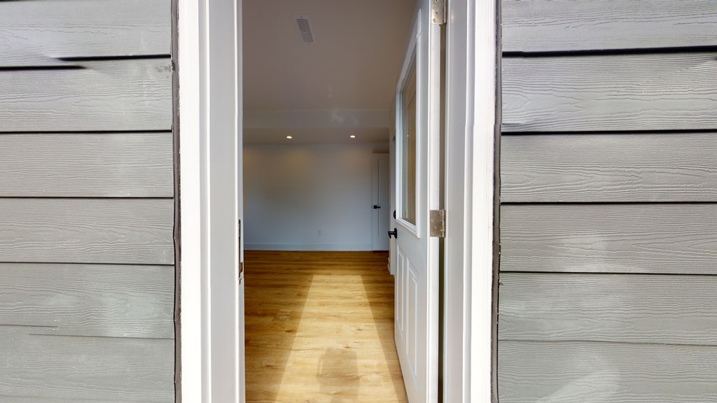 A hallway with wooden floors and white walls.