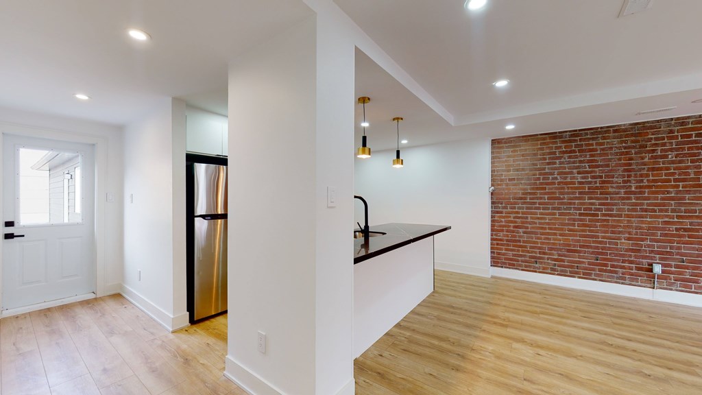 A kitchen with a refrigerator, sink, and a counter with a brick wall in the background.