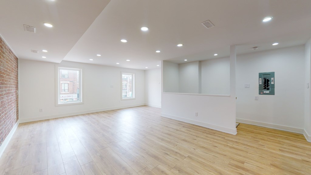 A large empty room with wooden floors and white walls.