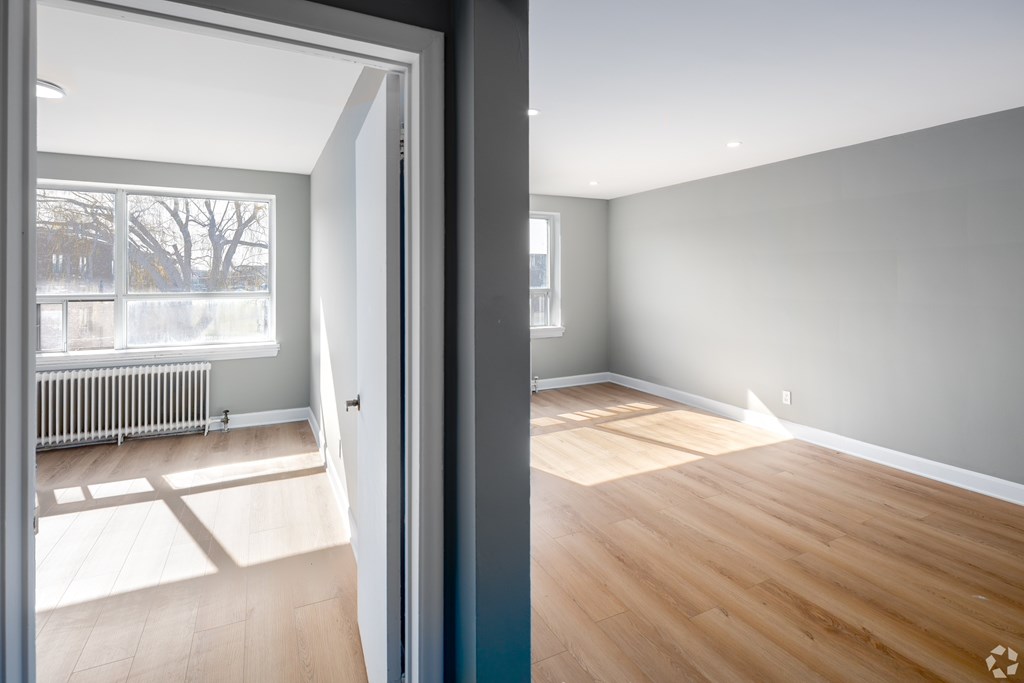 A room with wooden flooring and a grey wall.