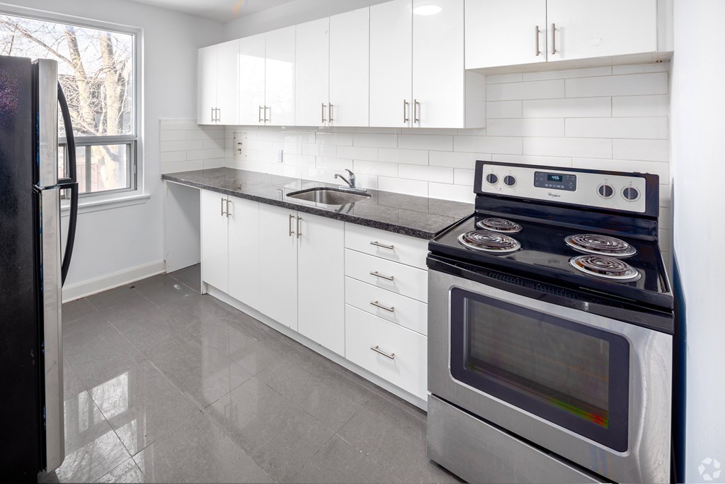 A modern kitchen with a black stove top oven and white cabinets.