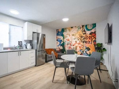 A kitchen with a table and chairs in front of a colorful mural.