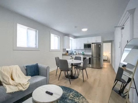 A modern living room with a grey couch, a coffee table, and a dining area with a table and chairs.